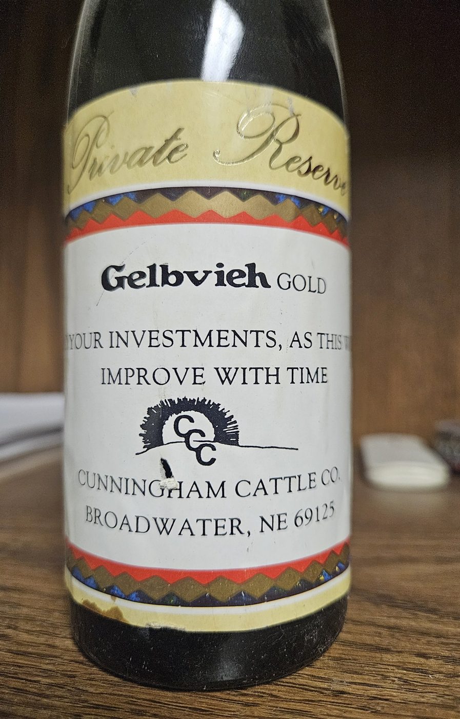 An old wine bottle with a Private Reserve label reading Gelbvieh Gold, with the CCC sunrise logo and Cunningham Cattle Co., Broadwater, NE 69125.