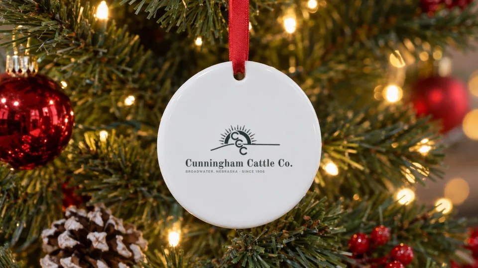 White Christmas ornament with the Cunningham Cattle Co. logo on a tree